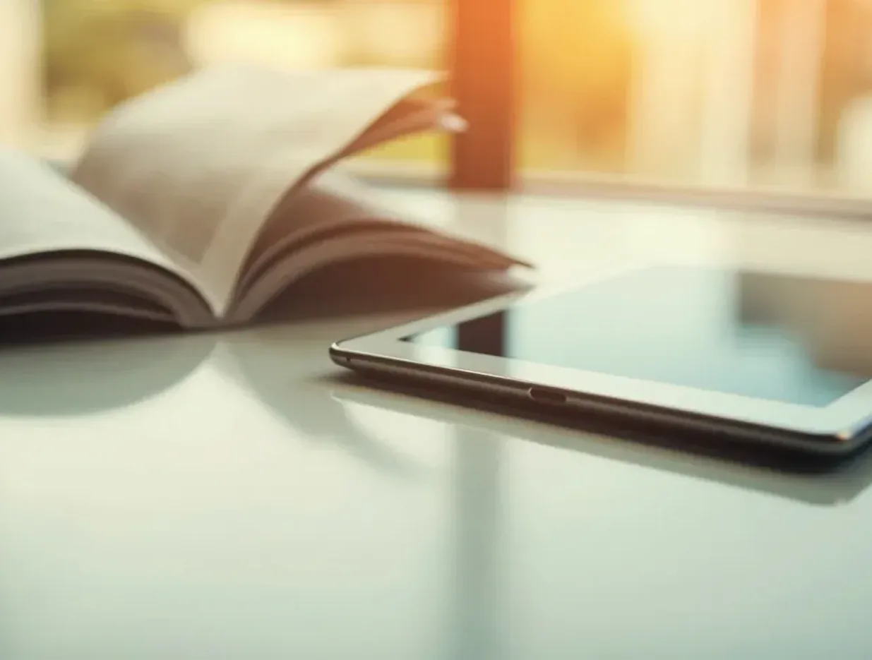 Editorial photograph of an open magazine, folded newspaper and tablet on a clean desk