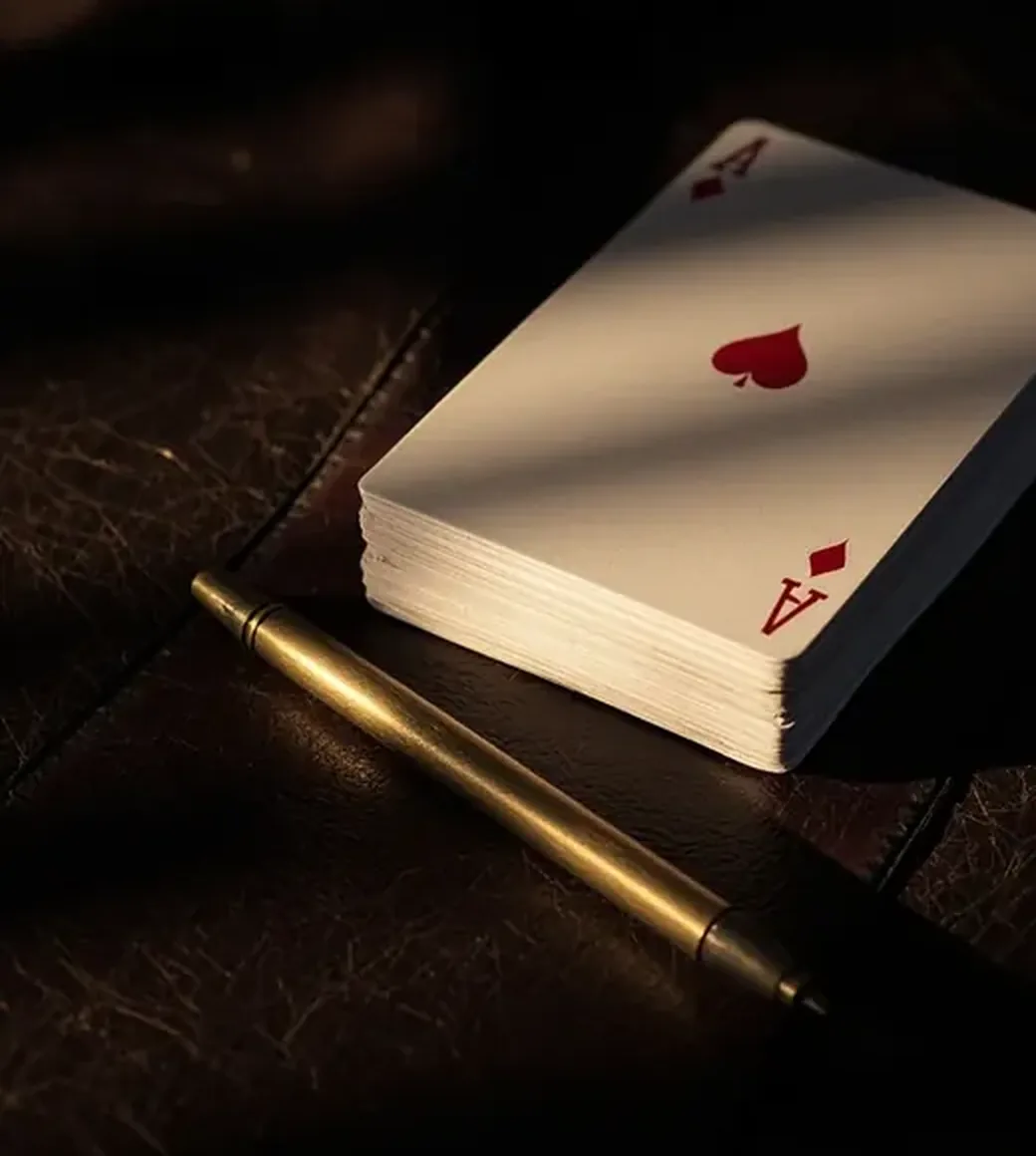 Portrait detail of a closed card pack and brass marker on dark leather
