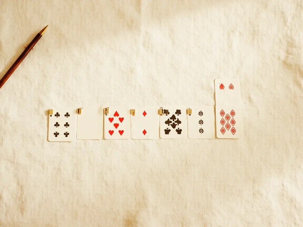 Photograph of three card sequences arranged on a linen board demonstrating a pure sequence, an impure sequence and a set